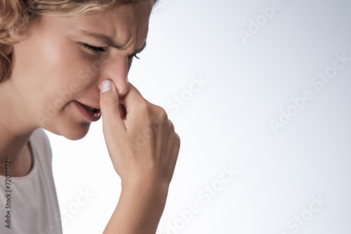 Strong disgust smell bad breath of young woman. Close-up portrait of a girl covering close her nose by fingers, expression face disgusting, dislike odor photo