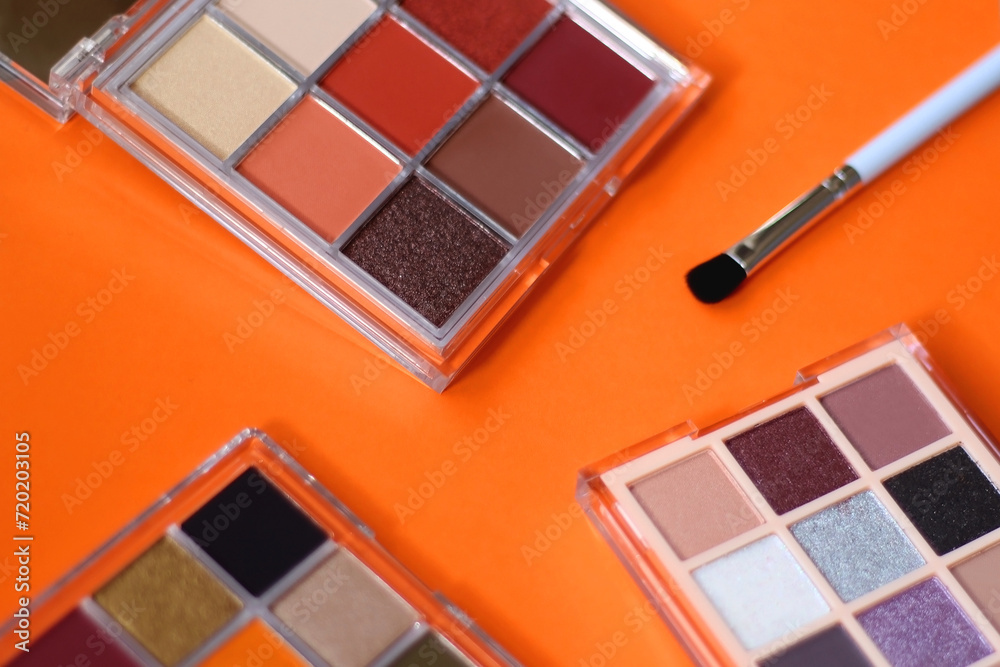 Colorful eyeshadow palettes and make up brush on orange background. Selective focus. Colorful eyeshadow palettes and make up brush on orange background. Selective focus.