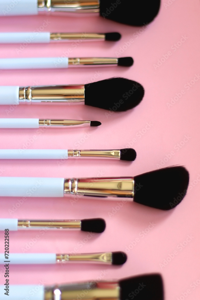 Various different make up brushes on pink background. Selective focus.