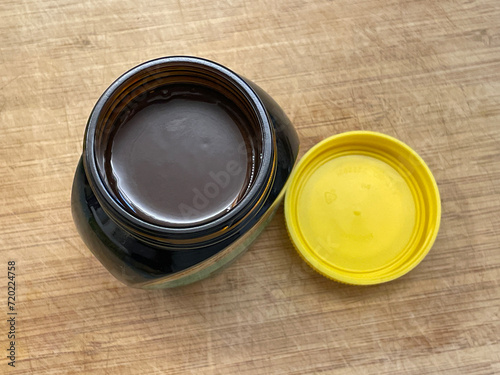 Open jar of marmite yeast extract spread, british speciality, on wooden chopping board. Love it or hate it