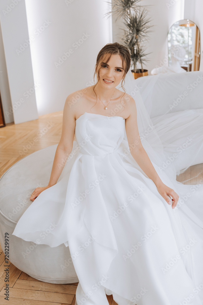 Portrait of the bride in the hotel room. A beautiful young girl is dressed in a white wedding dress. Modern wedding hairstyle. Natural makeup. Portrait of the bride in the hotel room. A beautiful young girl is dressed in a white wedding dress. Modern wedding hairstyle. Natural makeup.