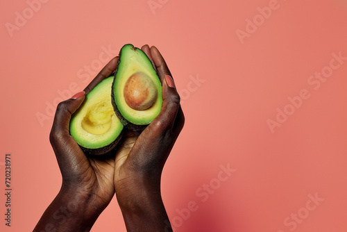 Black hand elegantly displaying a ripe avocado half