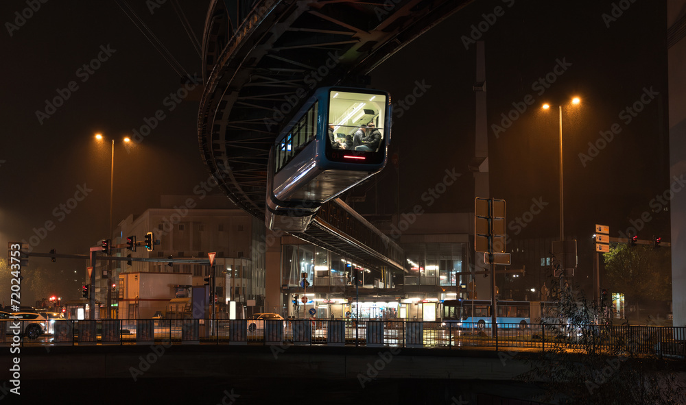 Night cityscape of Wuppertal, North Rhine-Westphalia, Germany: Schwebebahn cable car (electric elevated suspension monorail) at Alter Markt, Barmen city district