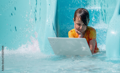 Concept photo: efficiency, excellent work space, work and study anywhere and anytime. A young girl studies and works remotely while relaxing in a pool of water park. © zwiebackesser