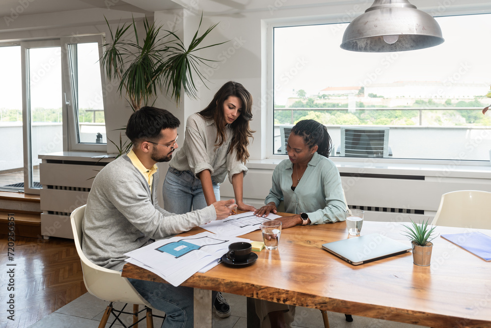 Group of young business people interior and exterior designers architects of prefab ecological houses working at home office on a project of energy efficient housing. Architectural engineers work