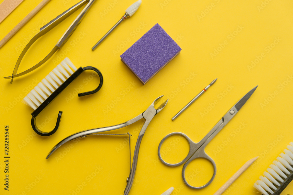 Professional manicure tools on yellow background. Manicure set. Top view. Cuticle pusher, cuticle trimmer and purpose scissor. Set of manicure and pedicure tools and cosmetics with space Professional manicure tools on yellow background. Manicure set. Top view. Cuticle pusher, cuticle trimmer and purpose scissor. Set of manicure and pedicure tools and cosmetics with space