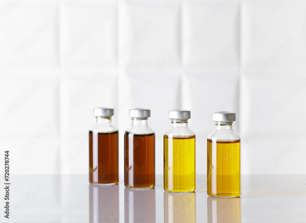 Group of glass bottles of injectable medicine on white laboratory table. White background. Group of glass bottles of injectable medicine on white laboratory table. White background.