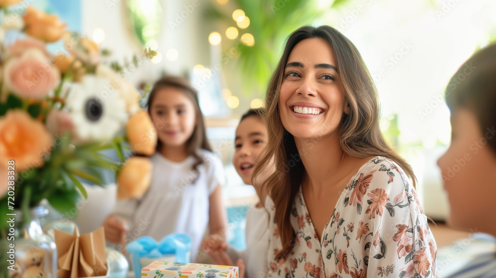 Smiling Latino woman in her 30s with three kids at home candid shot. Happy Mothers Day or birthday celebration Smiling Latino woman in her 30s with three kids at home candid shot. Happy Mothers Day or birthday celebration