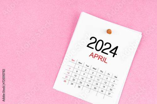 April 2024 calendar page and wooden push pin on pink.