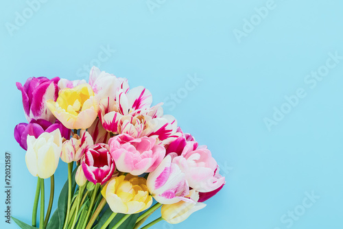Bouquet of colorful tulips on light blue background. Greeting card, copy space