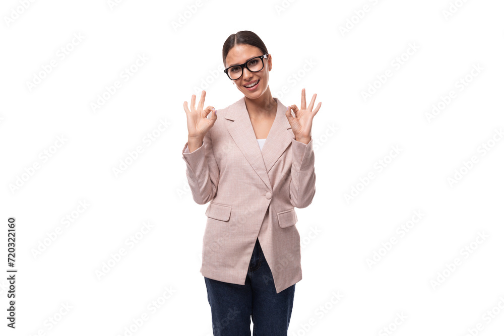 Naklejka premium pretty smart young woman with black hair and glasses for vision is dressed in a beige jacket and jeans on a white background