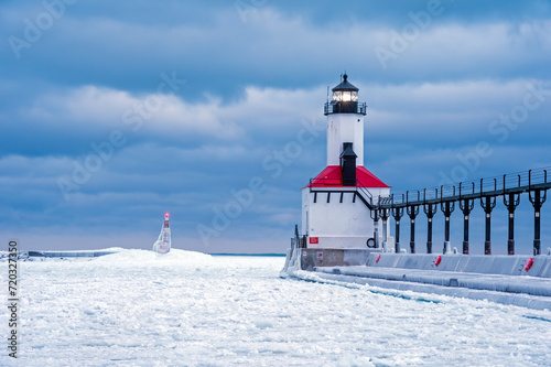 A bitter, frigid dawn finds the Michigan City, Indiana lighthouse and outer pier marker with beacons lit engulfed by a frozen Lake Michigan of the Great Lakes.