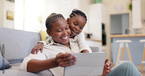 Family, woman with child and with tablet in living room of their home for social media. Technology or internet, streaming movie or bonding time and black mother with her daughter together happy photo