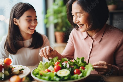 Happy senior woman and little girl bonding while preparing vegan salad together in the kitchen
