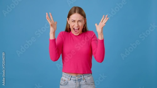 Angry female screaming hatefully with raised hands in studio photo