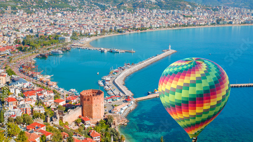 Hot air balloon flying over marina and Red Tower (Kizil Kule) in Alanya peninsula - Antalya, Turkey