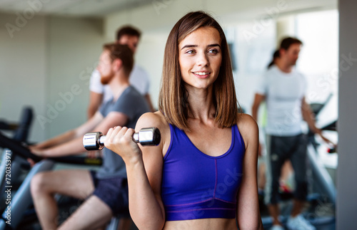 Fototapeta Naklejka Na Ścianę i Meble -  Fitness woman. Fit fitness girl smiling happy lifting weights looking strength training muscles.