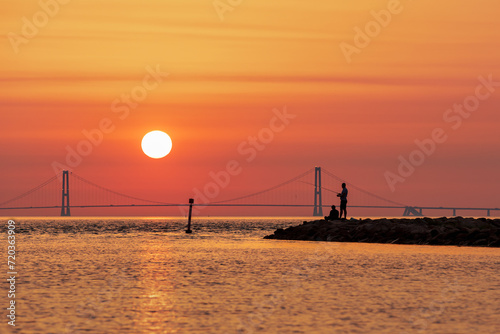 Silhouette of two men fishing with the Great Belt Bridge in the background, Denmark photo