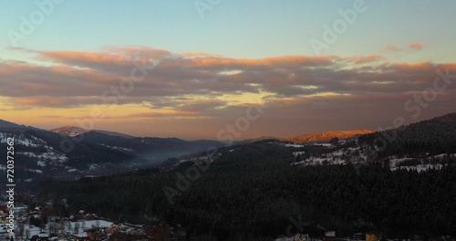 Aerial View of Mountains and Forest Covered with Snow at Sunset in Winter