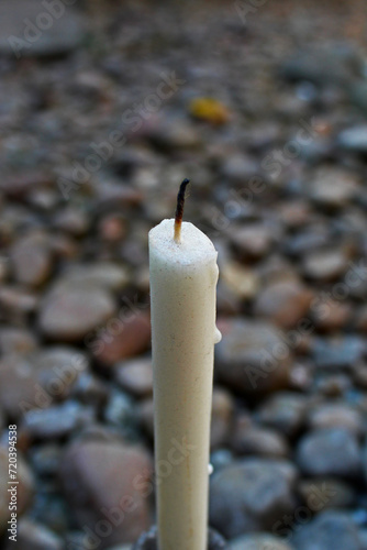 Close-up of a candle against background of pebbles. 