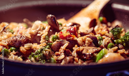 Close-up of a cooking pan featuring a freshly prepared dish of fried rice with mushrooms, green peas, and broccoli.