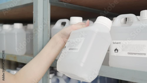 Close-up Hand of wonman using wireless bar code reader to checking chemical products (solvent) on the shelves.
