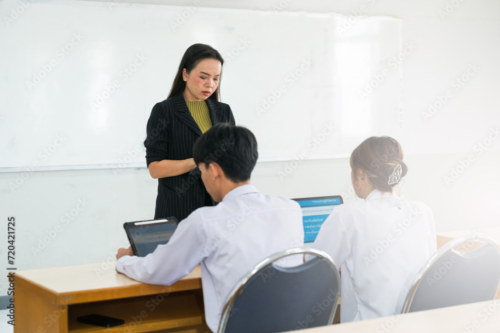 Asian female university explaining lesson to the students in the classroom