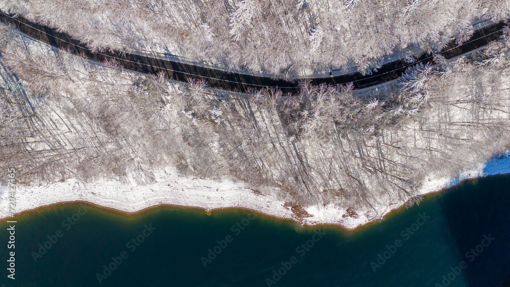 Mountain forest road from above. Aerial view on the road and forest at the winter time. Natural winter landscape from air. Forest under snow a the winter time. Landscape from drone. Bird eye