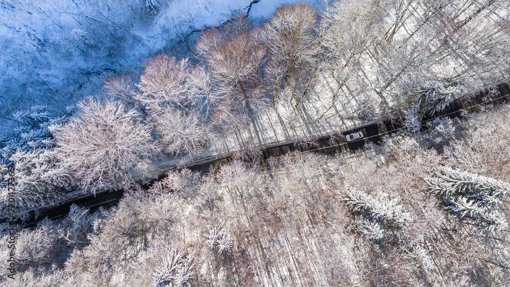 Mountain forest road from above. Aerial view on the road and forest at the winter time. Natural winter landscape from air. Forest under snow a the winter time. Landscape from drone. Bird eye