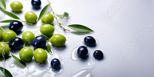 Galhos de oliva verde e roxa sobre superfície branca com gotas e reflexos de água. Ingrediente de azeite de oliva.