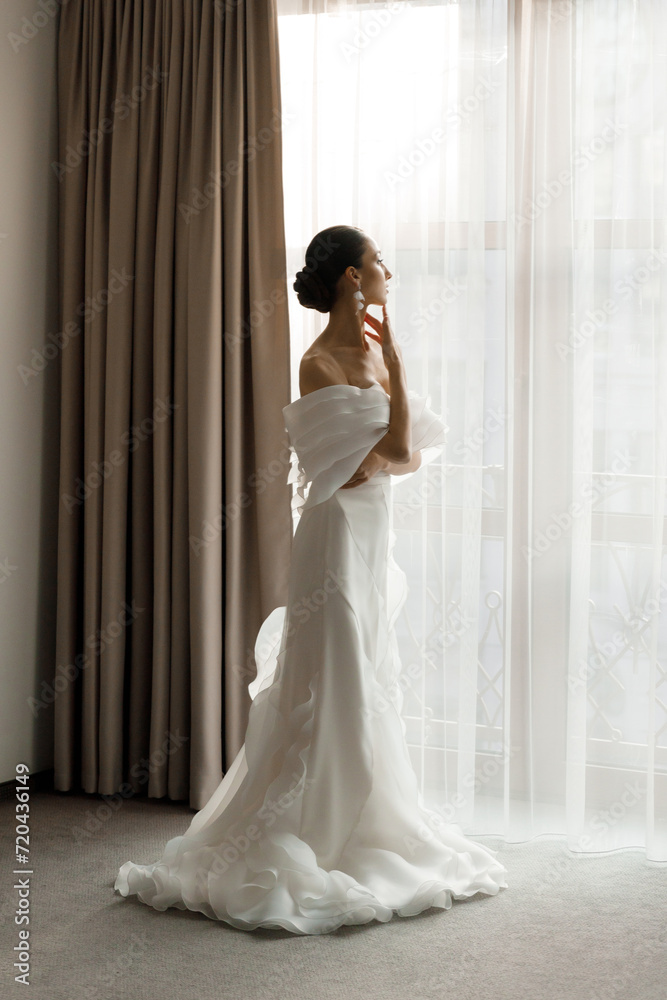 Morning and getting ready for a luxurious and beautiful bride in a hotel in a luxury room in pajamas and lingerie, putting on shoes and a chic white wedding dress Morning and getting ready for a luxurious and beautiful bride in a hotel in a luxury room in pajamas and lingerie, putting on shoes and a chic white wedding dress