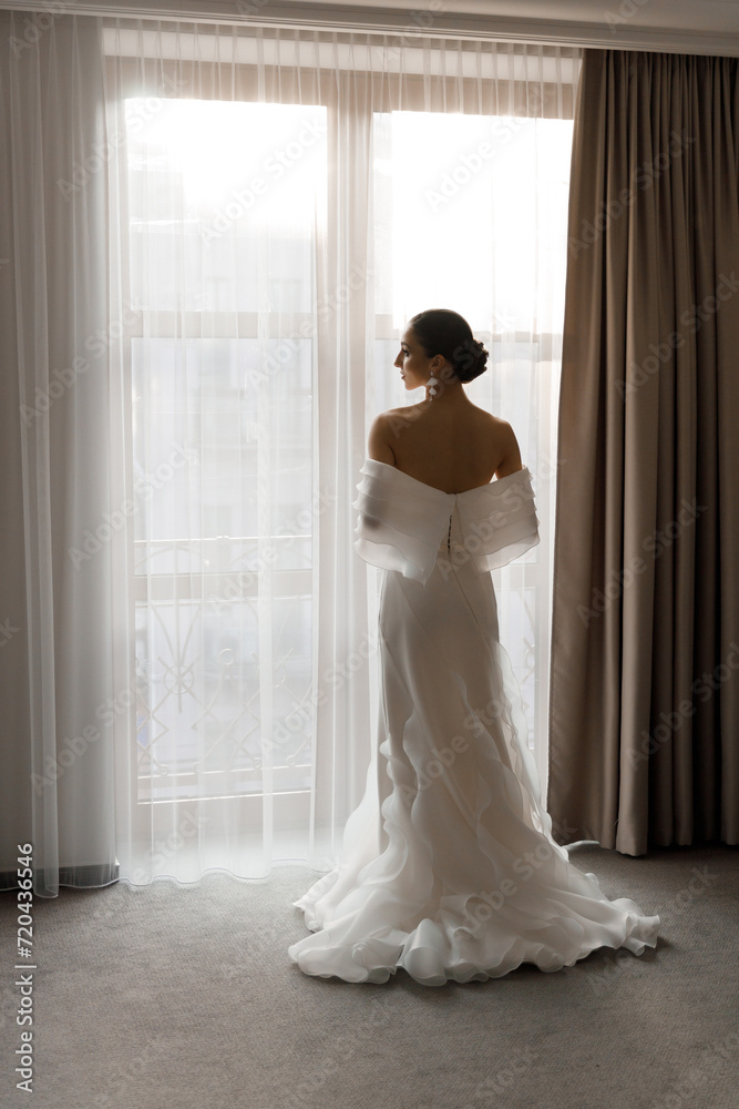 Morning and getting ready for a luxurious and beautiful bride in a hotel in a luxury room in pajamas and lingerie, putting on shoes and a chic white wedding dress Morning and getting ready for a luxurious and beautiful bride in a hotel in a luxury room in pajamas and lingerie, putting on shoes and a chic white wedding dress