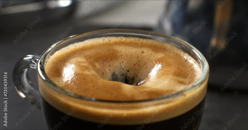Super slow motion macro of sweet sugar cubes are falling in hot creamy aromatic espresso coffee in transparent mug before being served to customer at cafe or bar at 1000 fps.