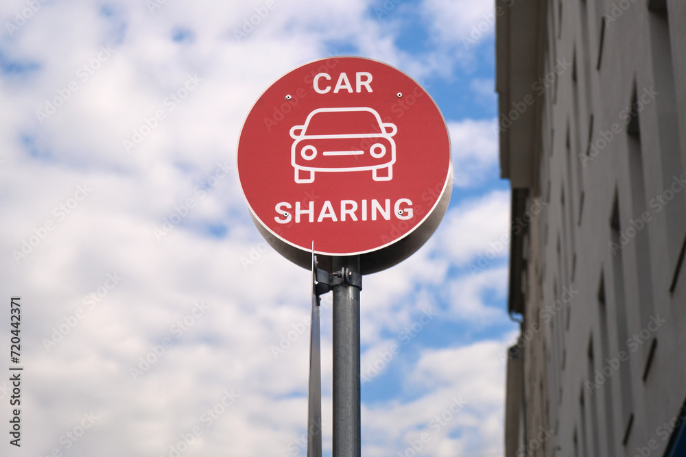 Red car sharing sign post in the city, urban mobility concept. Modern transportation service.