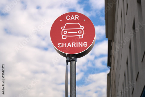 Red car sharing sign post in the city, urban mobility concept. Modern transportation service.