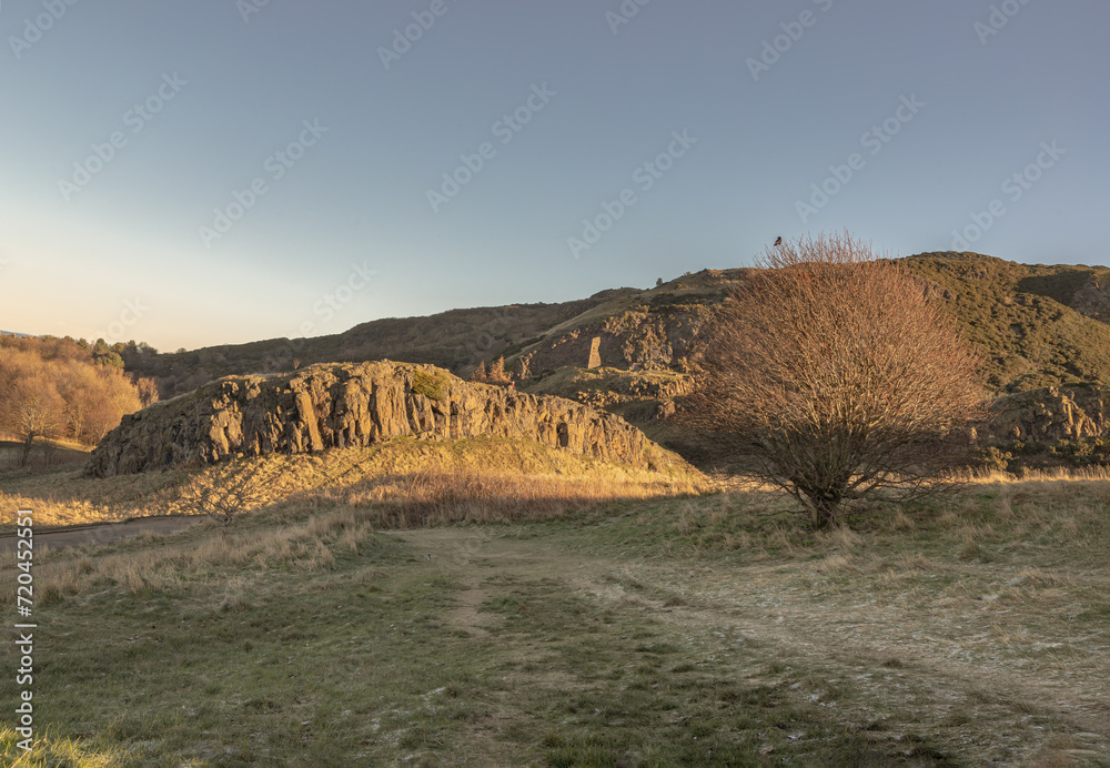 The breathtaking scenic landscape of Holyrood park with Salisbury Crags rugged hills and sky background. View of Edinburgh city. Space for text, Selective focus.