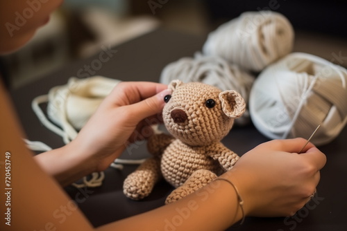 Close up view of hands crocheting a toy teddy bear.  photo