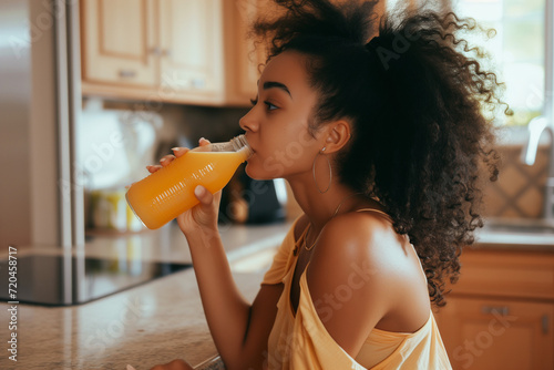 Young athletic woman sipping a fruit smoothie in the kitchen, radiating health and wellness in a vibrant and refreshing image.