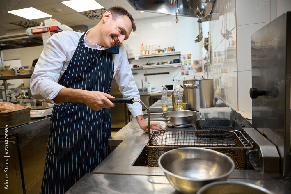 Kitchen worker communicates on a mobile phone Kitchen worker communicates on a mobile phone