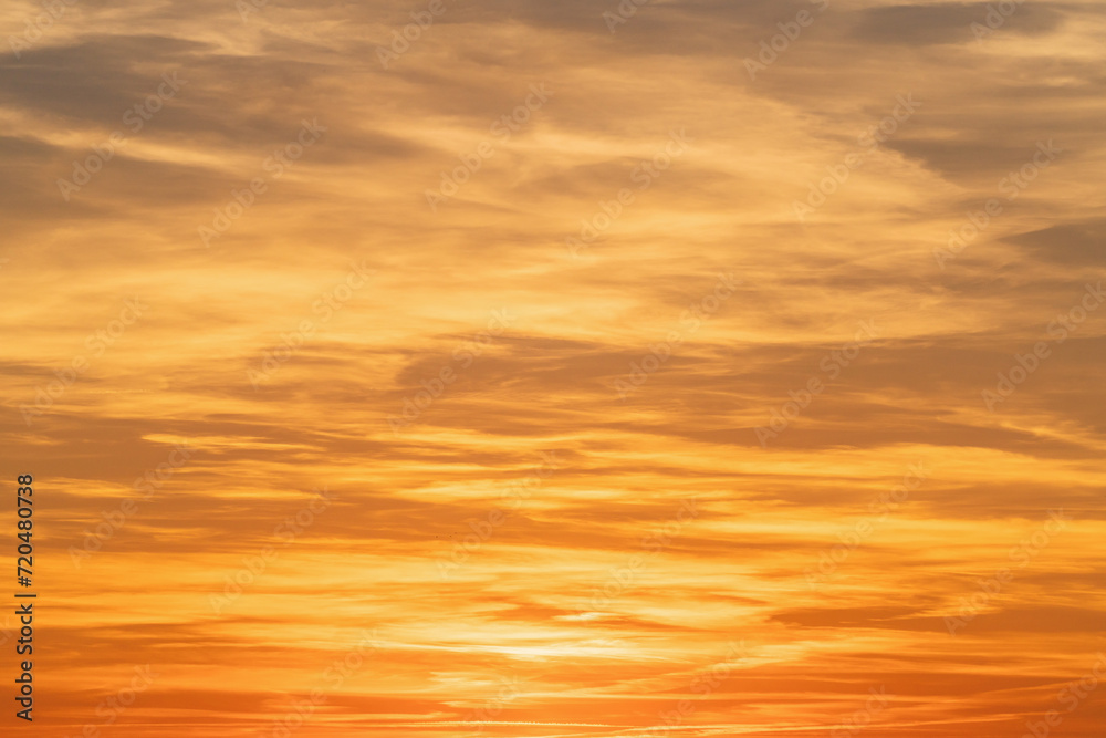 Sunset sky background with tiny clouds in orange and yellow colors.