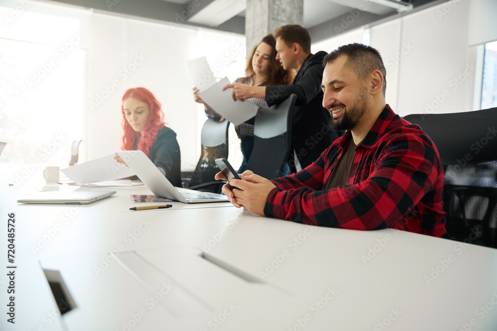 Fototapeta premium Smiling man looking for information online instead of looking through papers