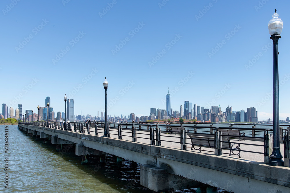 Panoramic view from the over water foot and bike path in Liberty State Park, Jersey City, NJ, USA with one single person on a bicycle, with views of Manhattan and Jersey City skyscrapers