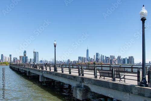 Panoramic view from the over water foot and bike path in Liberty State Park, Jersey City, NJ, USA with one single person on a bicycle, with views of Manhattan and Jersey City skyscrapers © Sonja