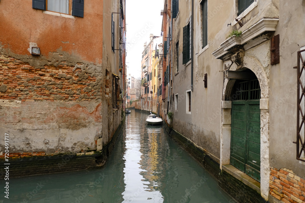 Typical narrow streets and canals between colorful and shabby houses in Venice, Italy.
