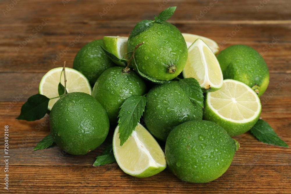 Pile of fresh wet limes and leaves on wooden table Pile of fresh wet limes and leaves on wooden table
