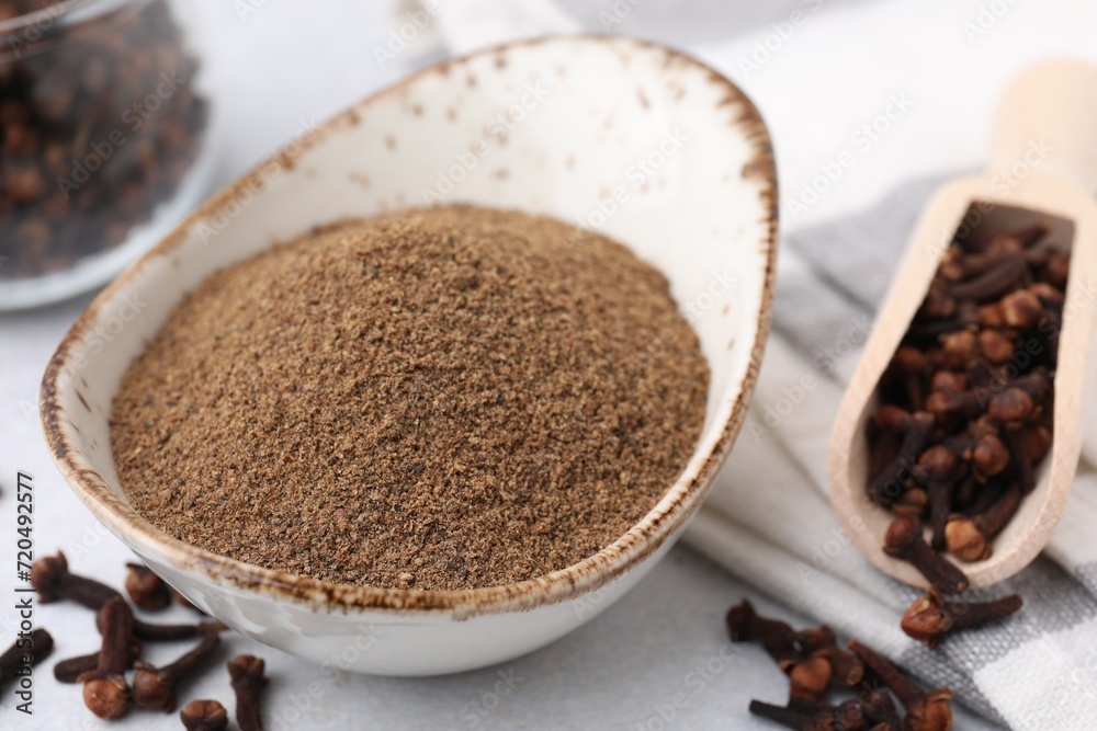 Aromatic clove powder and dried buds on light table, closeup Aromatic clove powder and dried buds on light table, closeup