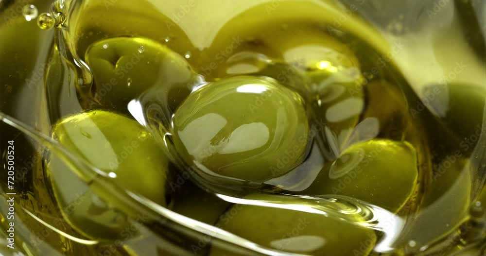 Super slow motion macro of fresh ripe olive is falling in bio organic golden liquid extra virgin olive oil with splashing drops on ripe olives at 1000 fps.