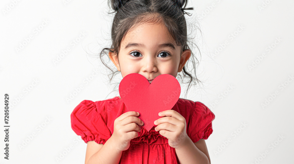 Little Girl Holding Red Heart Cutout.Young child in a red dress holding a red heart-shaped cutout to her face, symbolizing innocence and love. Little Girl Holding Red Heart Cutout.Young child in a red dress holding a red heart-shaped cutout to her face, symbolizing innocence and love.