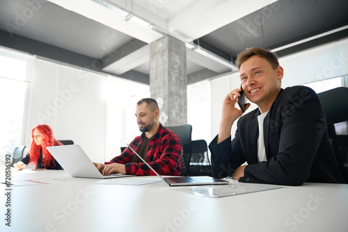 Confident man teamlead talking phone, arranging meeting with influential people photo