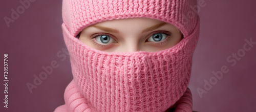 a young woman in a pink knitted balaclava. a model of a mask cap covering the face.